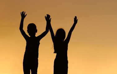 children silhouettes on a sunset background
