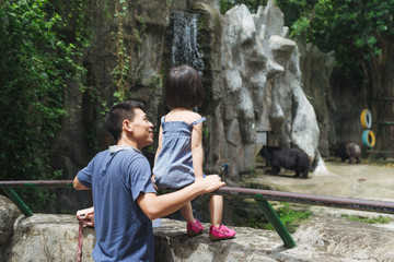 Happy family at the Zoo looking at a Bear