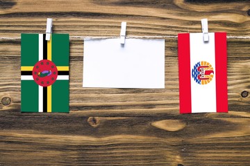 Hanging flags of Dominica and French Polynesia attached to rope with clothes pins with copy space...