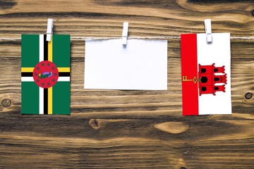 Hanging flags of Dominica and Gibraltar attached to rope with clothes pins with copy space on white...