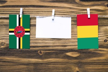 Hanging flags of Dominica and Guinea attached to rope with clothes pins with copy space on white...