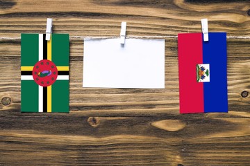 Hanging flags of Dominica and Haiti attached to rope with clothes pins with copy space on white...
