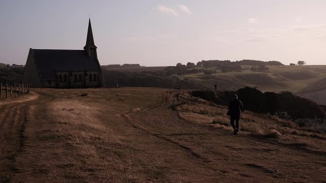 The small old chapel in Etretat on the top of the cliff fronting the big ocean. View of the beautiful coastline and alabaster cliff of Etretat, Normandie, France