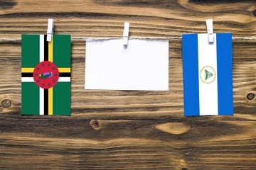 Hanging flags of Dominica and Nicaragua attached to rope with clothes pins with copy space on white...