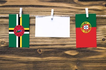 Hanging flags of Dominica and Portugal attached to rope with clothes pins with copy space on white...