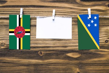 Hanging flags of Dominica and Solomon Islands attached to rope with clothes pins with copy space on...