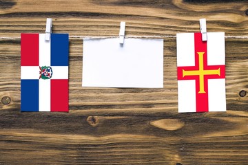 Hanging flags of Dominican Republic and Guernsey attached to rope with clothes pins with copy space...