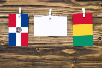 Hanging flags of Dominican Republic and Guinea attached to rope with clothes pins with copy space...
