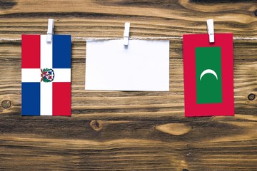 Hanging flags of Dominican Republic and Maldives attached to rope with clothes pins with copy space...