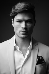Portrait of young handsome businessman wearing suit in black and white