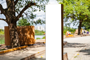 Blank vertical information sign in park in front wooden footpath