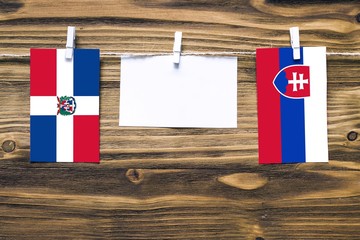 Hanging flags of Dominican Republic and Slovakia attached to rope with clothes pins with copy space...