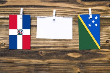 Hanging flags of Dominican Republic and Solomon Islands attached to rope with clothes pins with...