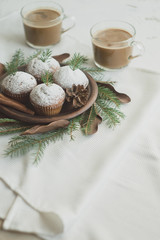 Christmas wreath imitation with a plate of cupcakes. Dessert decorated with fir branches and cones. Festive dessert with two cups of coffee.