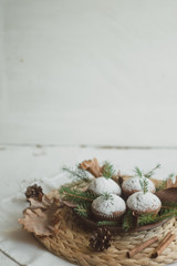 Christmas cupcakes on a straw wicker stand. Cupcakes decorated with fir branches and cones.