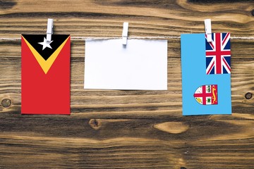 Hanging flags of East Timor and Fiji attached to rope with clothes pins with copy space on white...
