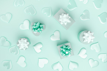 Beautiful silk hearts, gift box , white and green holiday bows on a green background, pastel colors . Celebrate concept. Flat lay .