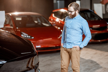 Man choosing electric car at the showroom