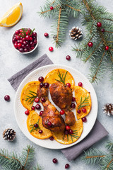 Naklejka na ściany i meble Baked chicken drumstick with oranges and cranberries in a plate light grey background. Christmas food Table with decorations.