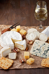Variety of different cheese with wine, fruits and nuts. Camembert, goat cheese, roquefort, gorgonzolla, gauda