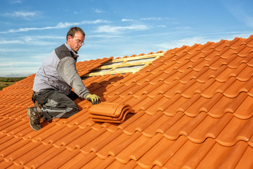 Roofer at work, installing clay roof tiles, Germany