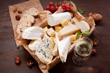 Variety of different cheese with wine, fruits and nuts. Camembert, goat cheese, roquefort, gorgonzolla, gauda, parmesan, emmental