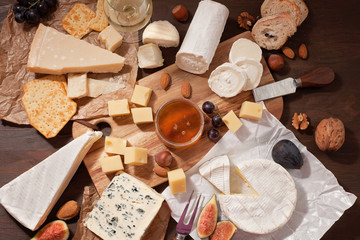 Variety of different cheese with wine, fruits and nuts. Camembert, goat cheese, roquefort, gorgonzolla, gauda, parmesan, emmental