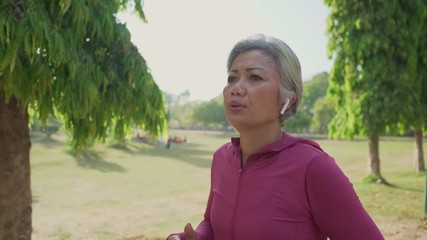 slow motion gimbal tracking shot on attractive middle aged lady running happy at city park . beautiful and sporty 40s woman exercising doing jogging workout enjoying healthy lifestyle and fitness