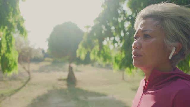 gimbal tracking shot on attractive middle aged lady running happy at city park . beautiful and sporty 40s woman exercising doing jogging workout enjoying healthy lifestyle and fitness