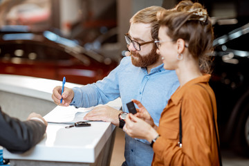 Couple signning documents at the car dealership