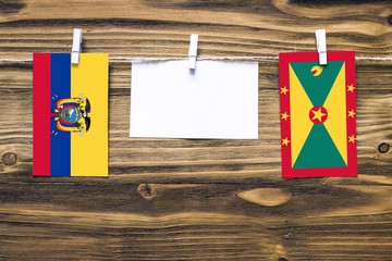 Hanging flags of Ecuador and Grenada attached to rope with clothes pins with copy space on white note paper on wooden background.Diplomatic relations between countries.