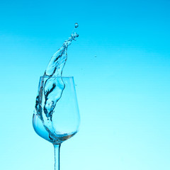beautiful splashes of water in a wine glass, with blue filter, close up with copy space.