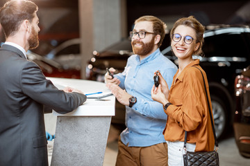 Sales manager with a young couple buying a new car