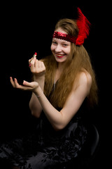 Naklejka premium Beautiful girl of school age paints lips with lipstick and looks