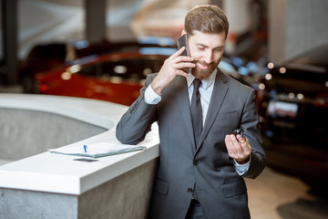 Businessman with car key in the showroom
