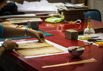 Fototapeta na wymiar Traditional Chinese book and calligraphy restorer laboratory. Master hands at work close-up.