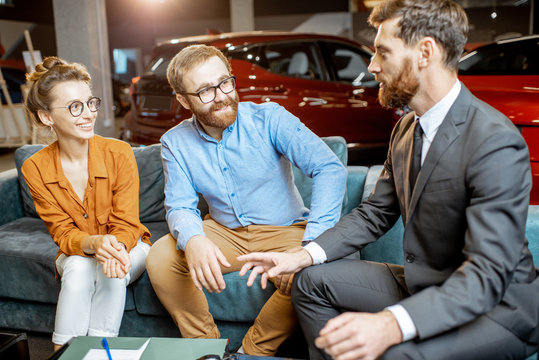 Young couple with saller on the couch at the car dealership