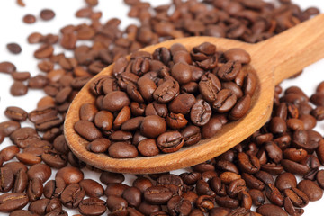 Coffee beans on wooden spoon. Isolated on white background. Macro.