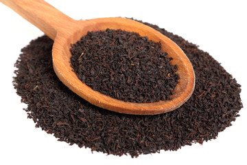 Loose dried black tea leaves on wooden spoon. Isolated on white background.