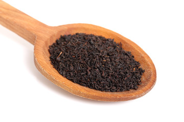 Loose dried black tea leaves on wooden spoon. Isolated on white background.