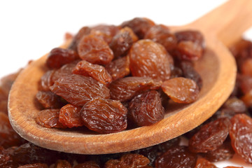 Raisins on wooden spoon. Isolated on white background. Macro.