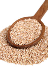Spelt groats on wooden spoon. Isolated on white background.