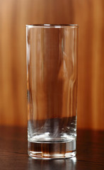Empty highball glass at wooden brown background