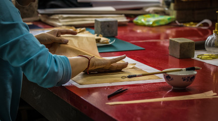 Traditional Chinese book and calligraphy restorer laboratory. Master hands at work close-up.