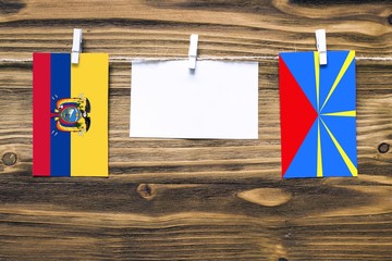 Hanging flags of Ecuador and Reunion attached to rope with clothes pins with copy space on white...