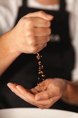 Buckwheat grains fall from one hand to another.