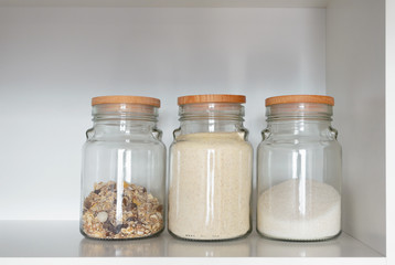 Glass jar with various product for breakfast: sugar, semolina and muesli. Food products in the kitchen storing. Horizontal composition