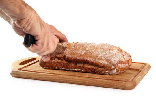 Chef slicing loaf of rye bread on cutting board. Isolated on white background.