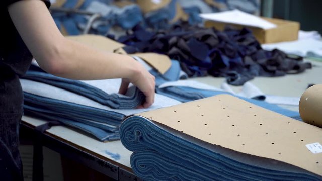 The worker of the sewing factory collects pieces of fabric cut by the automatic laser machine into sets. 4k footage.