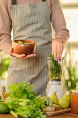 girl cooks green smoothie in a blender. vegan 